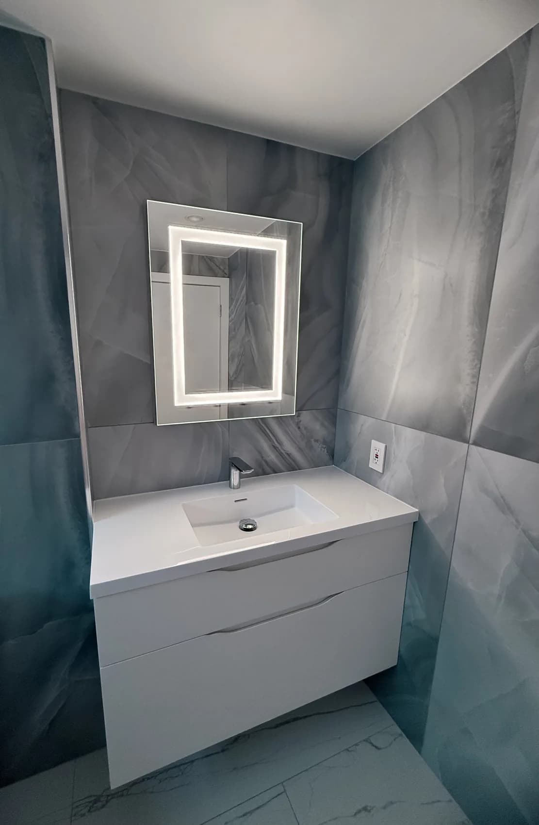 Blue-grey tile bathroom with floating white vanity