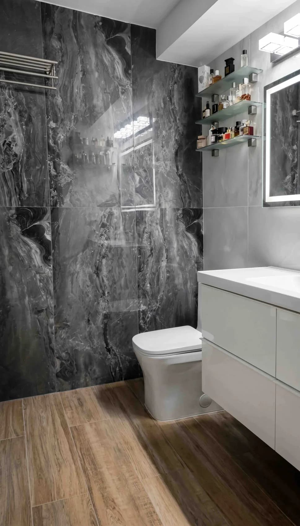 Dark wall surfaces paired with a white vanity and warm wood-look flooring.