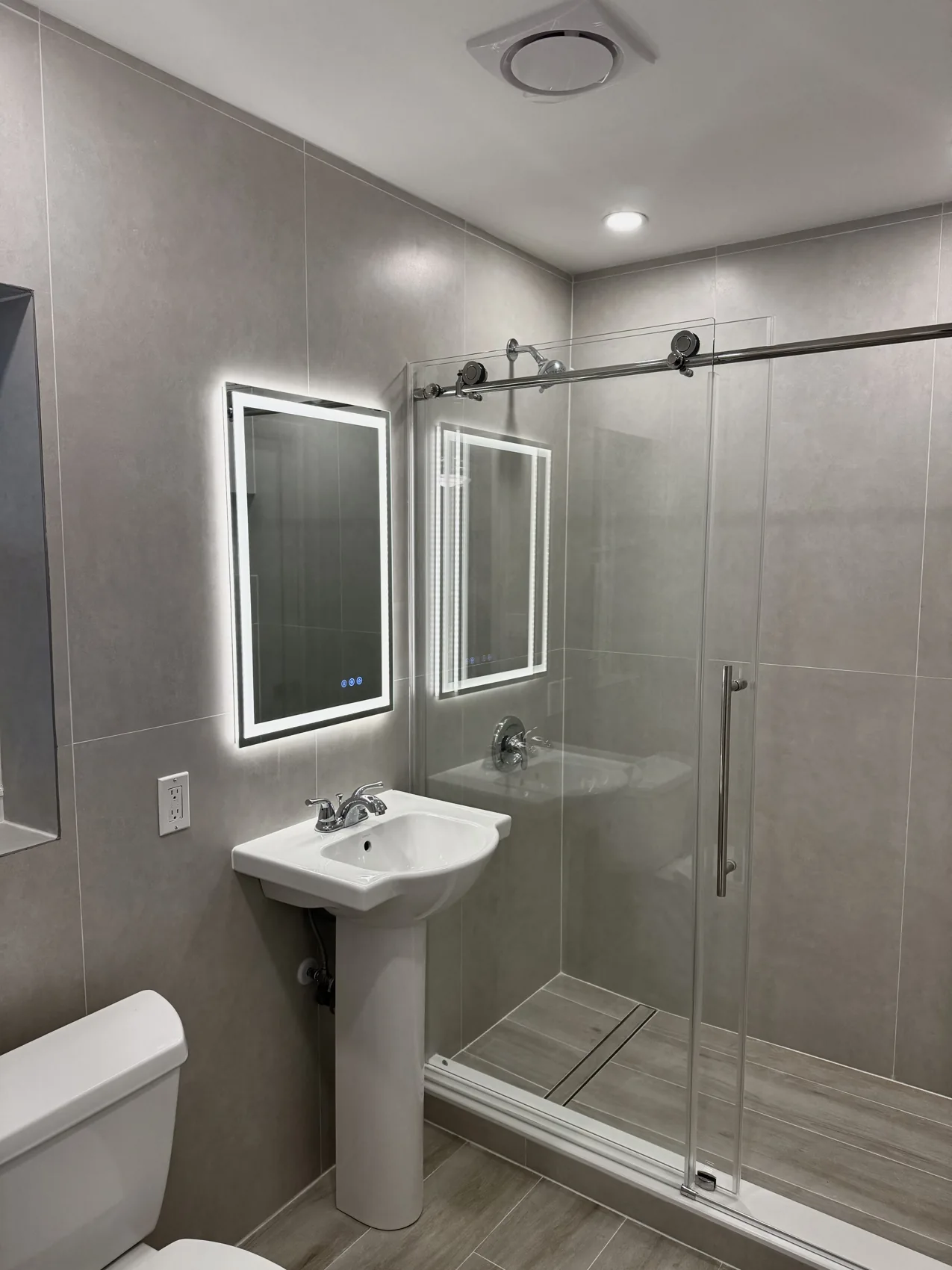 Renovated tiled bathroom with a glass shower enclosure