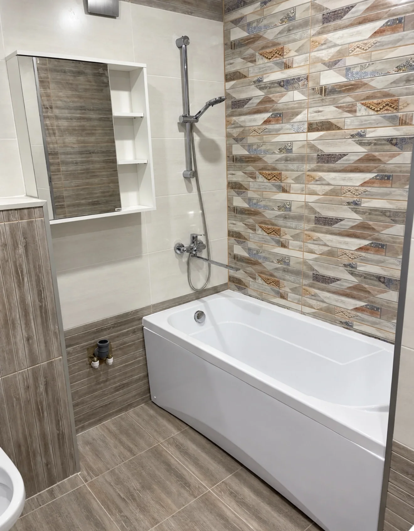 A patterned feature wall adds texture above a built-in bathtub.