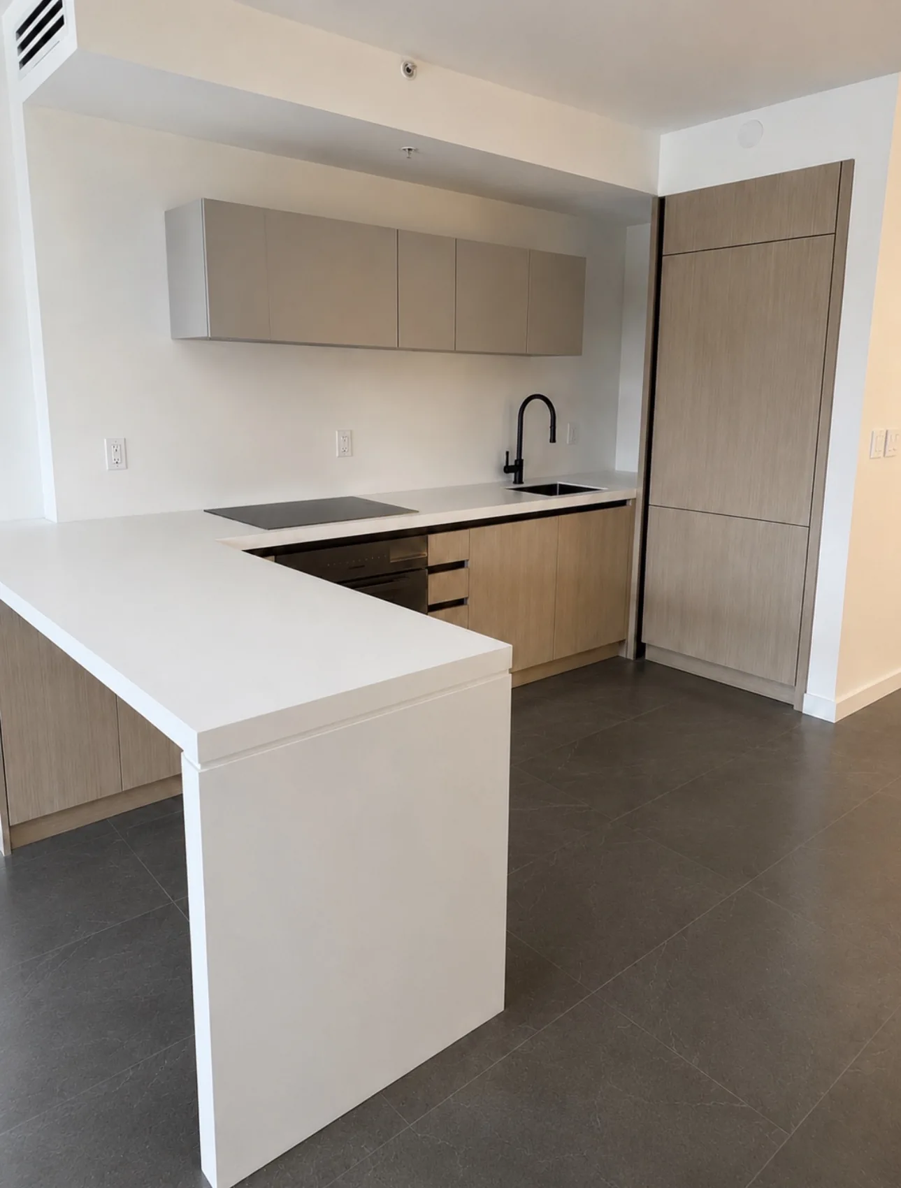 A compact kitchen with pale cabinetry, wood accents and an integrated appliance layout.
