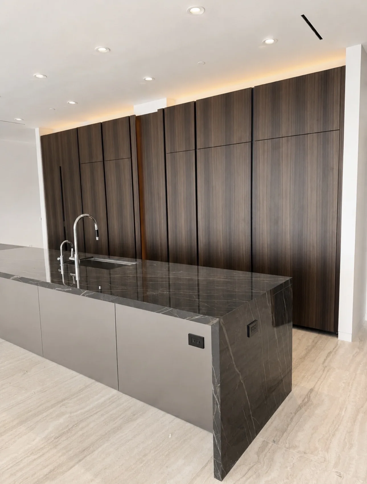 Dark wood kitchen cabinetry with a stone waterfall island