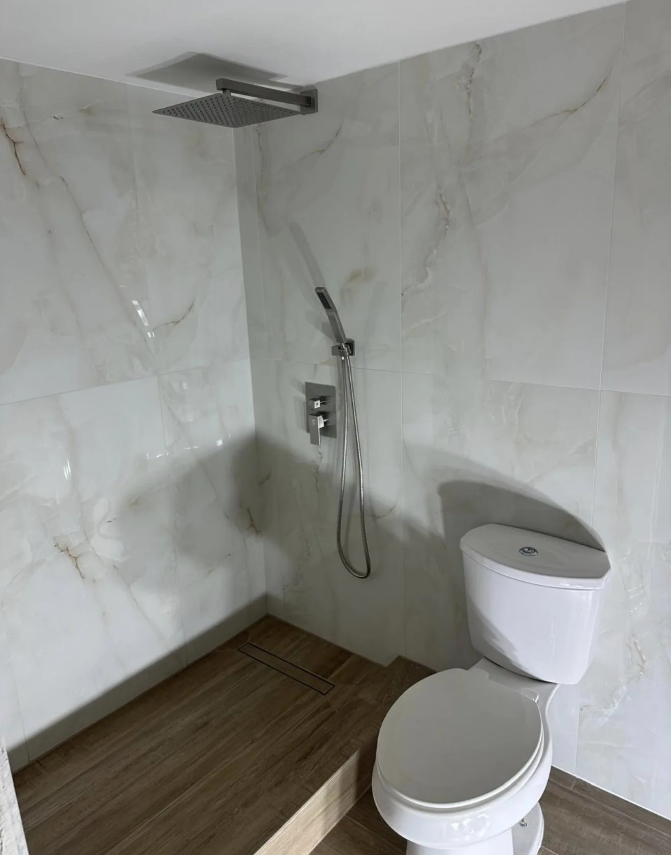 Light wall tile, wood-look flooring and a compact vanity in a coordinated bathroom.